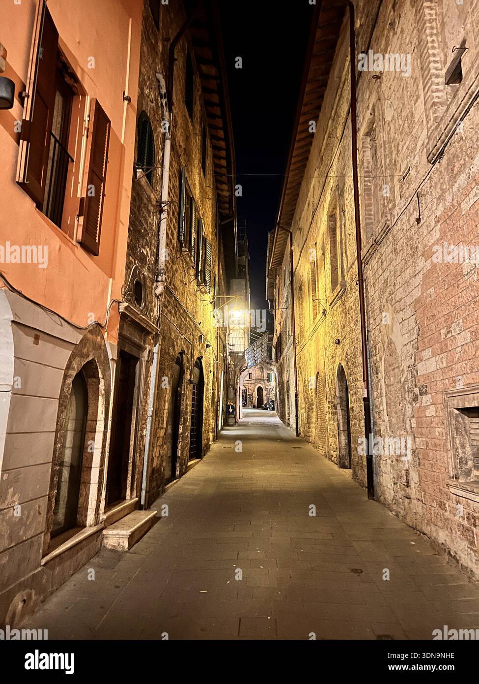 Enge historische Steinallee beleuchtet von warmen Nachtlichtern - Smartphone-aufgenommenes Stockfoto