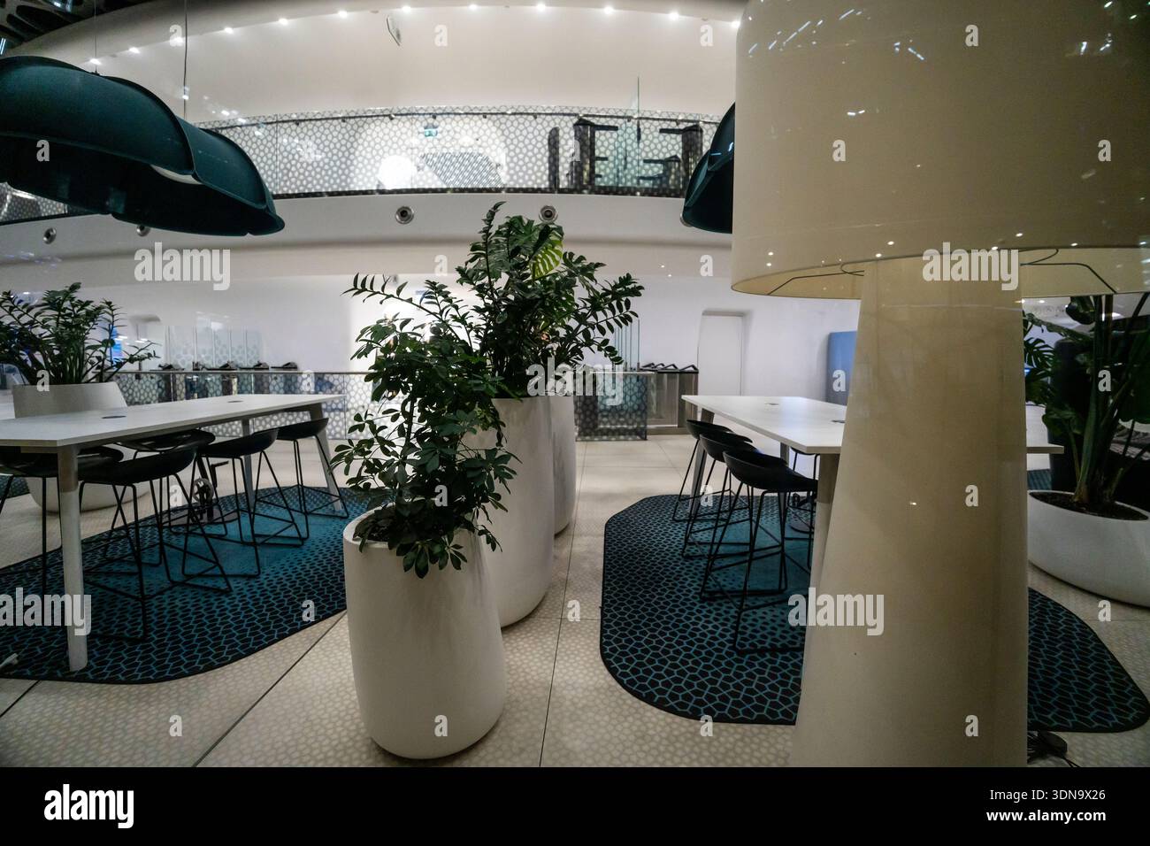 Warschau, Polen: Moderne Hotellobby mit stilvollen türkisfarbenen Sitzgelegenheiten, elegantem Betonboden, dramatischer Deckenbeleuchtung und moderner Architektur Stockfoto