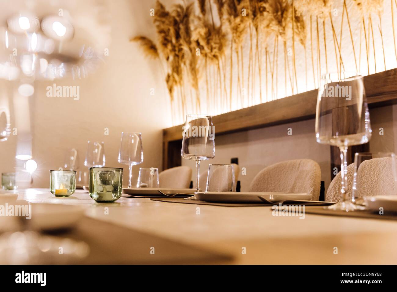 Eleganter Restauranttisch mit Weingläsern, Kerzen und Pampasgras im Hintergrund Stockfoto