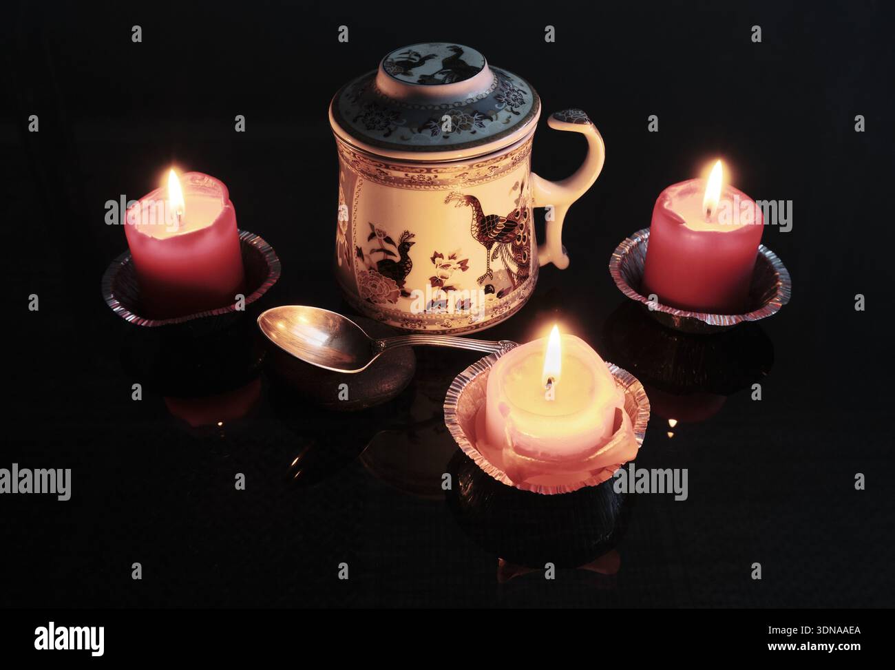 Chinesischer Tee wird auf einem Holztisch um Kerzen in einem dunklen Raum serviert. Selektiver Fokus. Stockfoto