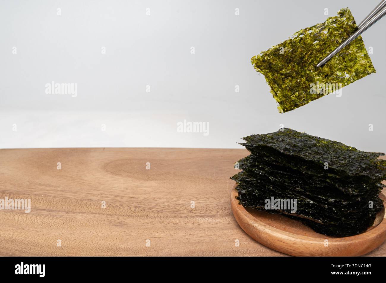 Essstäbchen, die koreanische Algen (Gim) Blatt halten, isoliert auf weißem Hintergrund Stockfoto