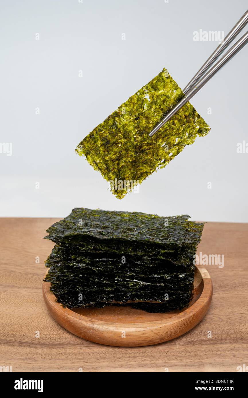 Essstäbchen, die koreanische Algen (Gim) Blatt halten, isoliert auf weißem Hintergrund Stockfoto