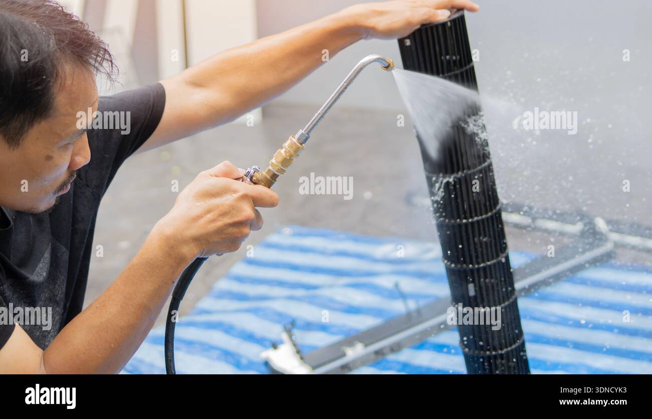 Die Techniker reinigen das Teil der Klimaanlage durch Spritzen von Wasser. Die Teile der Klimaanlage werden von Hand und Wasserspray gereinigt. Selektiver Fokus. Stockfoto