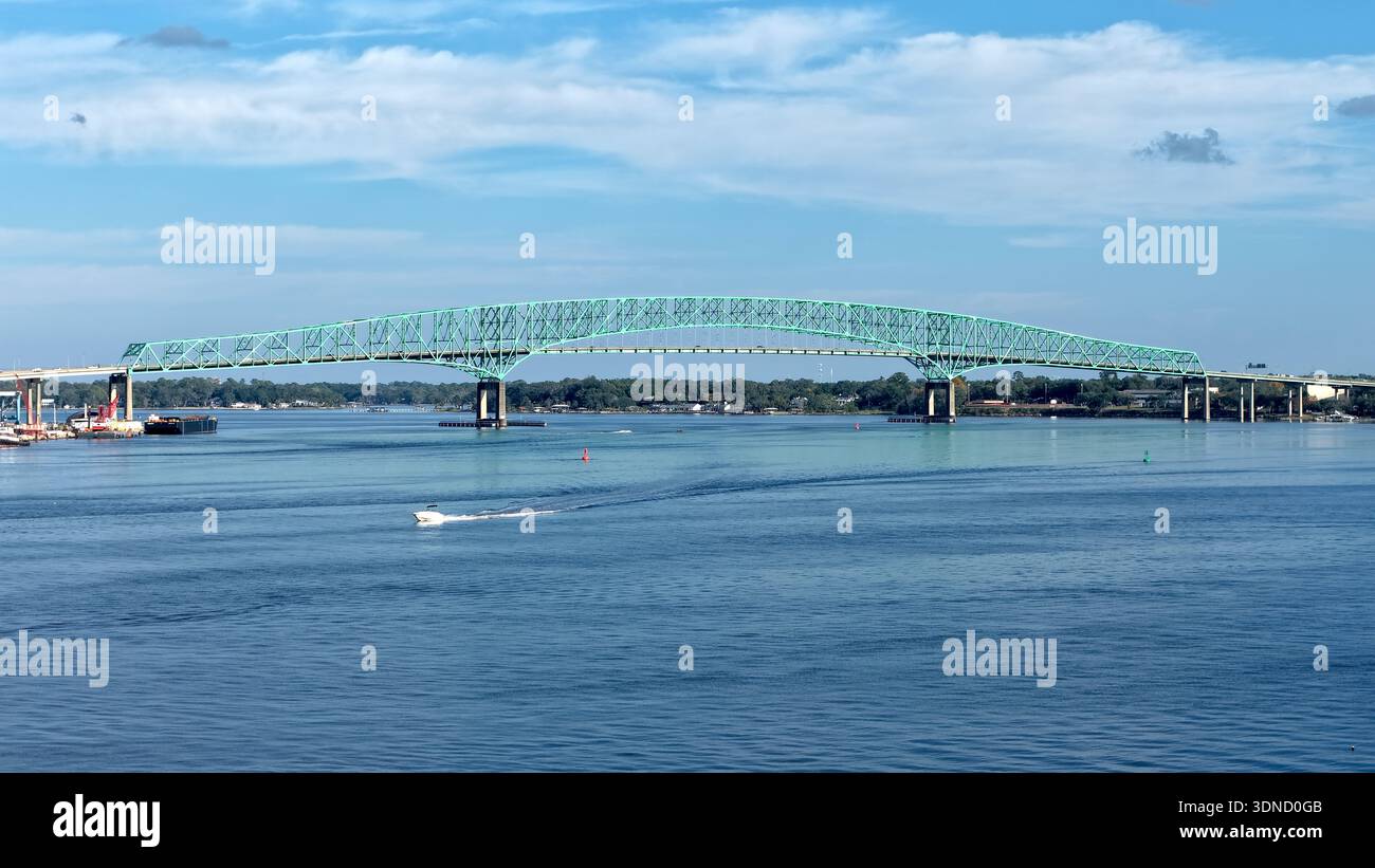 Die hellblau-grüne Fachwerkbrücke aus der Vogelperspektive überspannt den St. Johns River unter einem riesigen Himmel, einem Band aus Wildwasserpfaden hinter dem Boot Jacksonvil Stockfoto