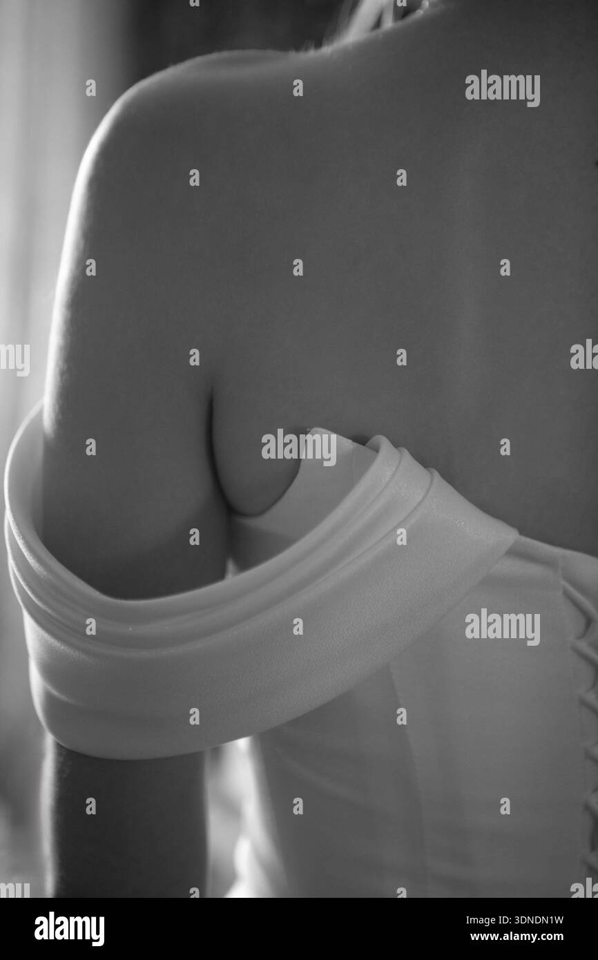 Eine vertikale Nahaufnahme von zarten Spitzengurten an einem Brautkleid Stockfoto