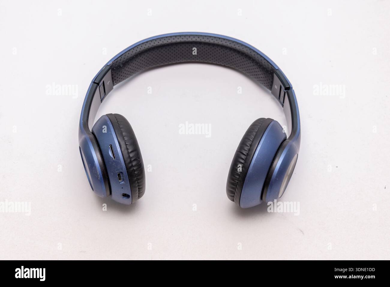 Blaue, kabellose Over-Ear-Kopfhörer liegen auf einem hellen, isolierten Hintergrund Stockfoto