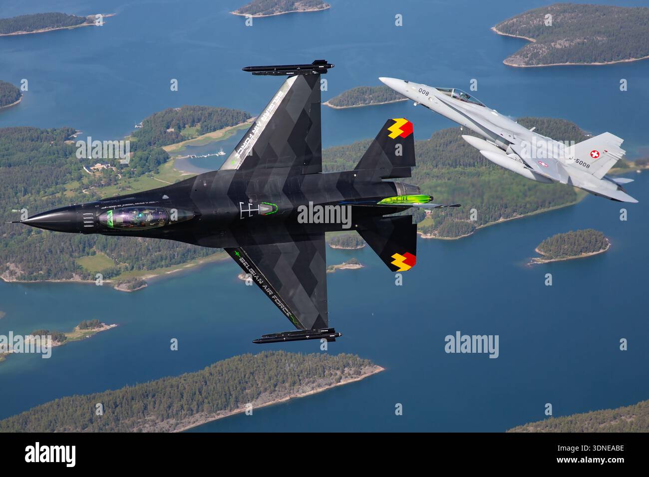 F-16AM FA-87, Serie 6H-87, belgische Luftwaffe, und Schweizer F/A-18C J-5008, Serie 1336/SFC008, fliegen in Formation mit Bankmanövern auf der Turku Airshow 2023. F-16AM mit Turbofan F100-PW-220 und F/A-18C mit F404-GE-402. Nahaufnahmen von Piloten und Luft-Luft-Aufnahmen zeigen Präzision, Agilität, Multifunktionsfähigkeit und Kunstflugzeug mit individueller Lackierung und Heck-Kunst. Stockfoto