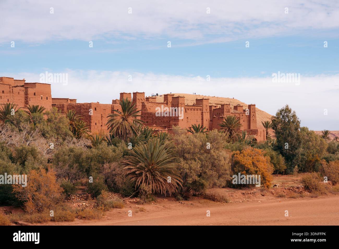 Marokkanische Kasbah Ait Ben Haddou mit Palmen und Touristen erkunden Stockfoto
