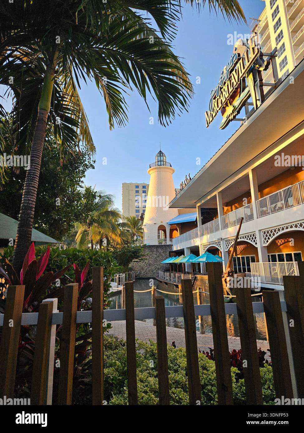 NUR FÜR REDAKTIONELLE ZWECKE - MARGARITAVILLE HOLLYWOOD BEACH FLORIDA: Außenansicht des Margaritaville Hollywood Beach Resort mit seinem charakteristischen architektonischen Leuchtturm-Element und einem Speisesaal am Kanal. Dieses AAA Four Diamond Resort liegt am 1111 N. Ocean Drive und ist ein bedeutendes Wahrzeichen Südfloridas zwischen dem Atlantischen Ozean und dem Intracoastal Waterway. Die Szene zeigt die tropische Landschaftsgestaltung und die Architektur im nautischen Stil, die die Marke „keine Sorgen“ charakterisieren, inspiriert von Sänger Jimmy Buffett. Stockfoto