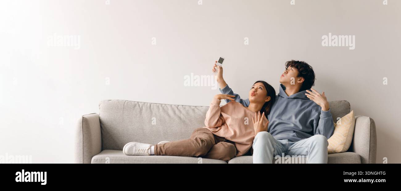 Ein Paar teilt einen Moment bei einem Selfie auf einem Sofa in einem gemütlichen Wohnzimmer Stockfoto