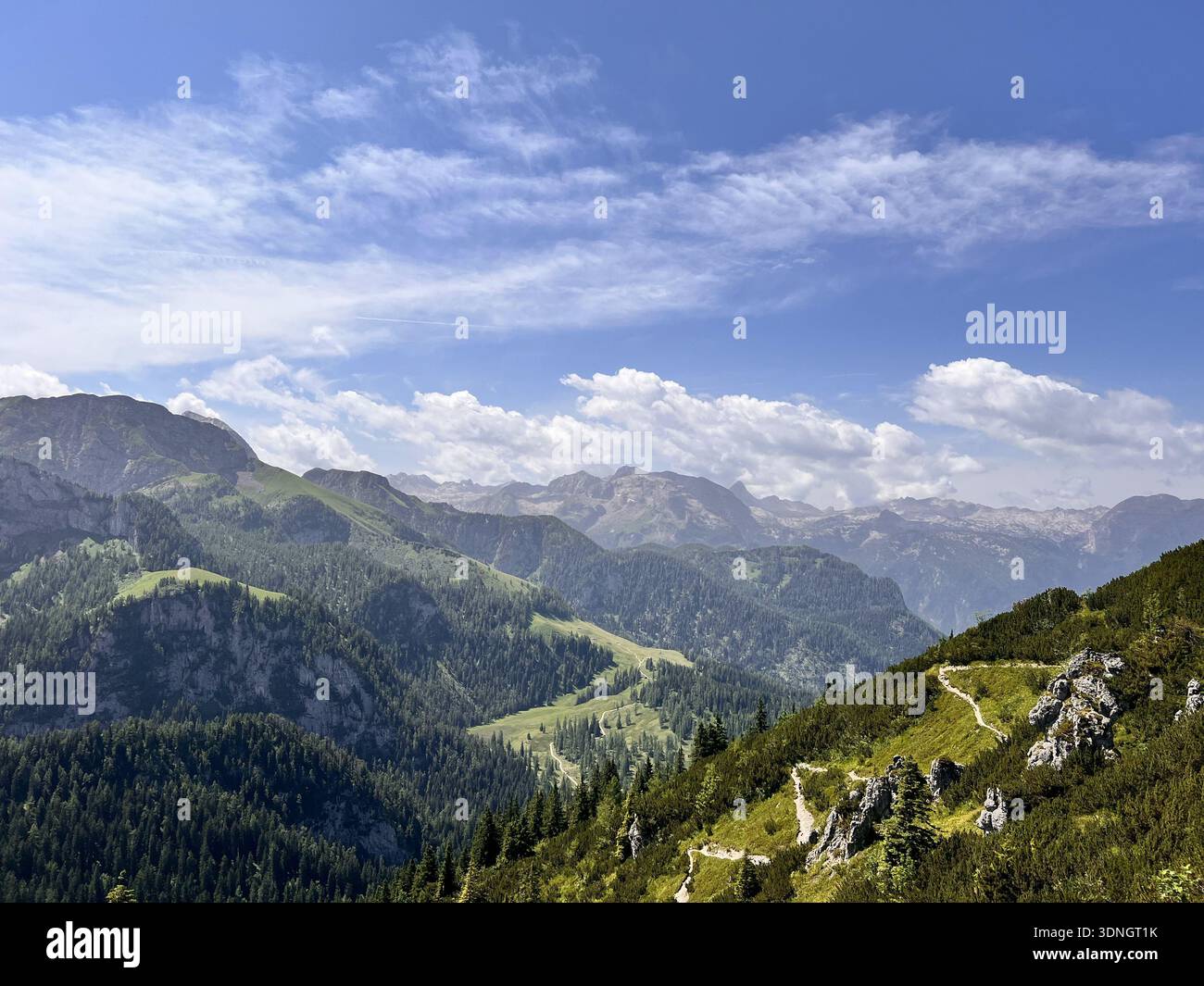 Berglandschaft mit üppigen grünen Hügeln, felsigen Hängen und fernen Schichtgipfeln Stockfoto