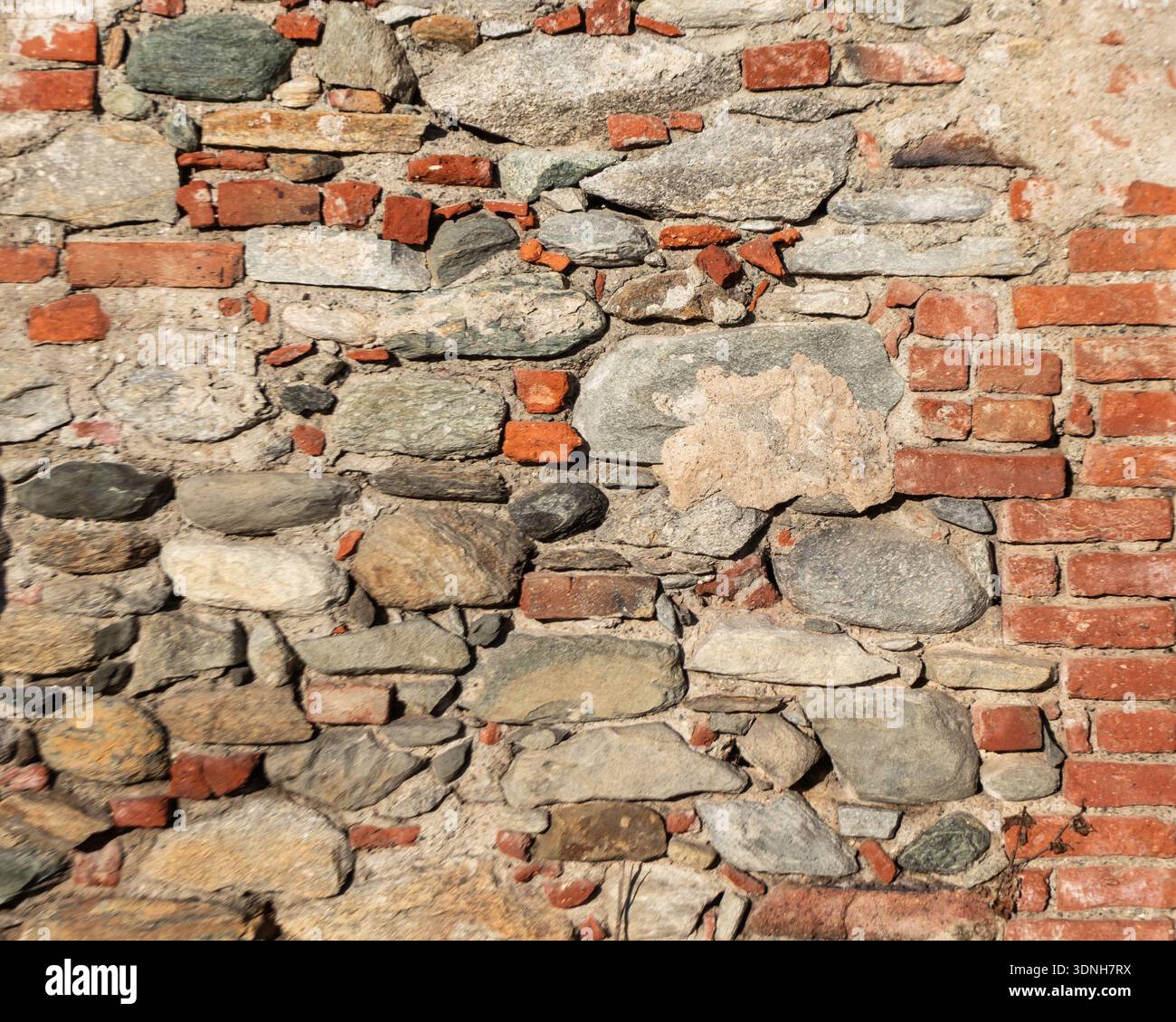 Verwitterte Stein- und Ziegelsteinmauer mit satten Texturen und natürlichen Farben, ideal als architektonischer Hintergrund für Design, Restaurierung und Urban Stockfoto
