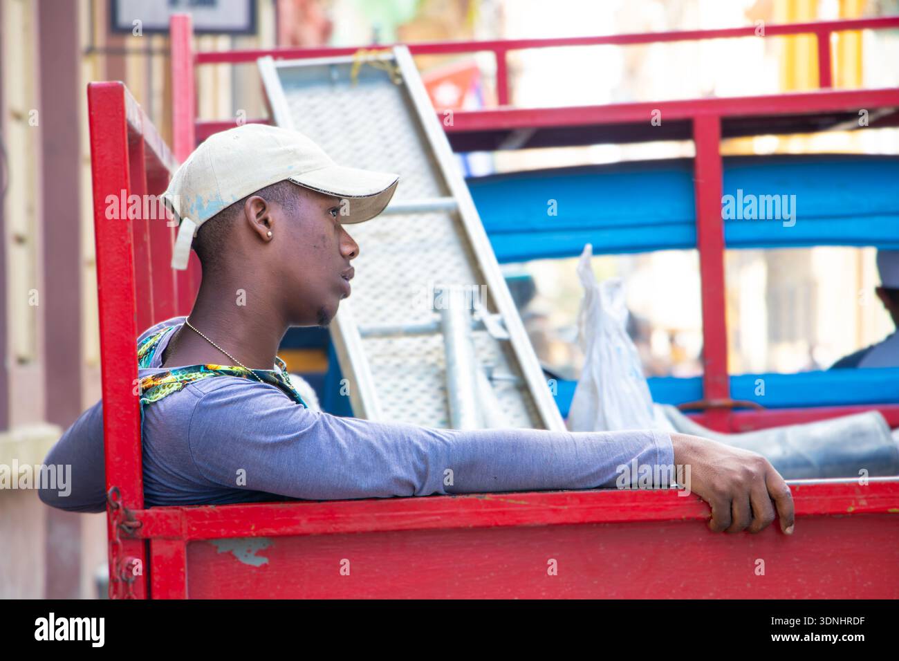 Der junge hispanische Arbeiter mit einer Baseballmütze liegt auf der Seite eines RPick-up-Trucks in havanna kuba Stockfoto