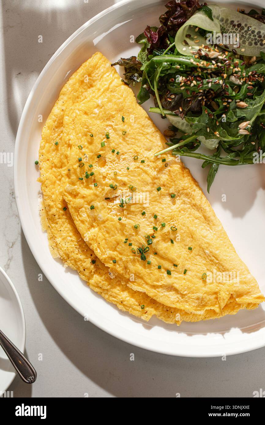 Französisches Omelett mit Kräutern und grünem Salat Stockfoto