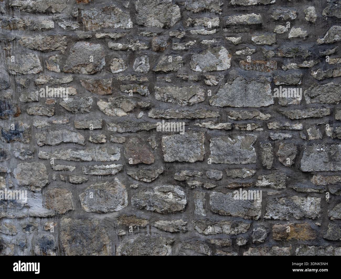 Grungy Steinmauerwerk, das eine raue Hintergrundoberfläche bildet. Stockfoto