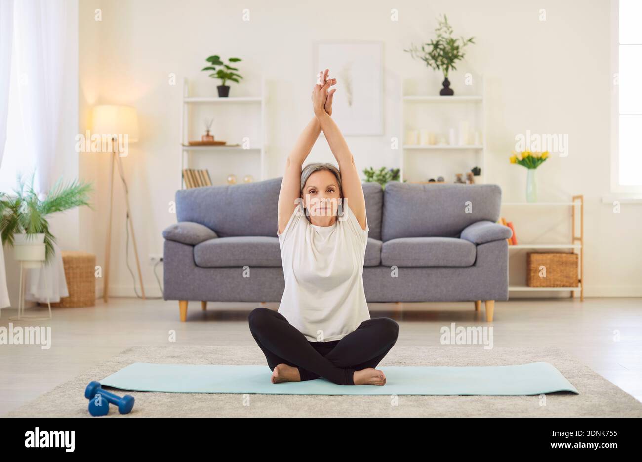 Yogi alte sportliche Seniorin, die zu Hause Yoga praktiziert, in Lotusübung sitzt, entspannt posiert Stockfoto