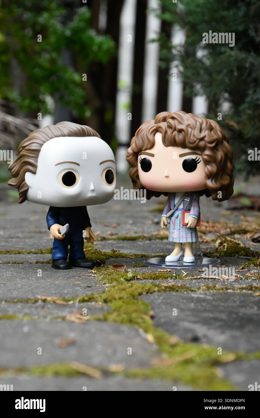 Funko Pop Actionfiguren von Michael Myers aus dem Horrorfilm Halloween und Nancy aus der tv-Serie Stranger Things. Steinplatten Straße, grünes Moos. Stockfoto