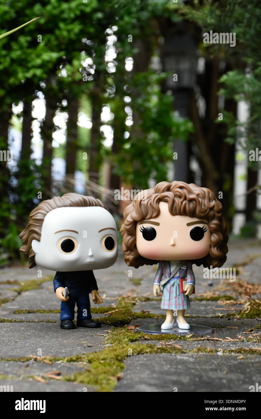 Funko Pop Actionfiguren von Michael Myers aus dem Horrorfilm Halloween und Nancy aus der tv-Serie Stranger Things. Steinplatten Straße, grünes Moos. Stockfoto