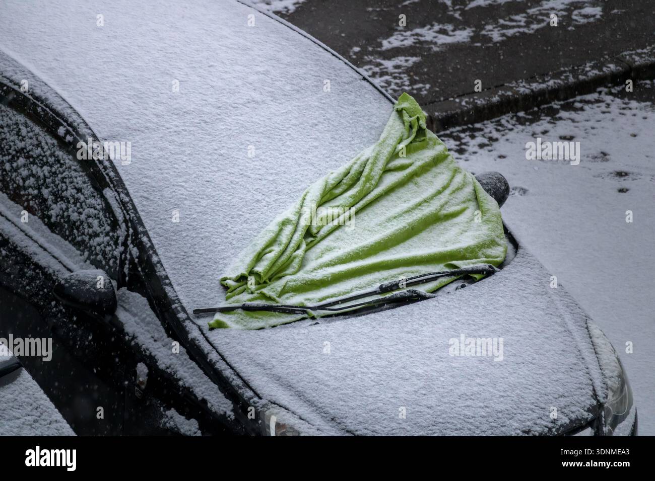 Windschutzscheibe des Autos mit einem Schutztuch bedeckt mit Schnee Stockfoto