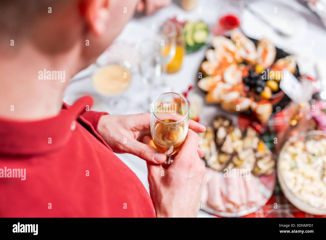 Ein Mann steht bei einem festlichen Abendessen und hält ein Glas Champagner. Stockfoto