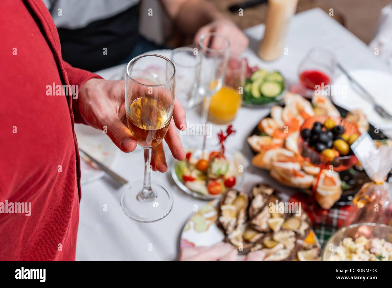 Ein Mann steht bei einem festlichen Abendessen und hält ein Glas Champagner. Stockfoto