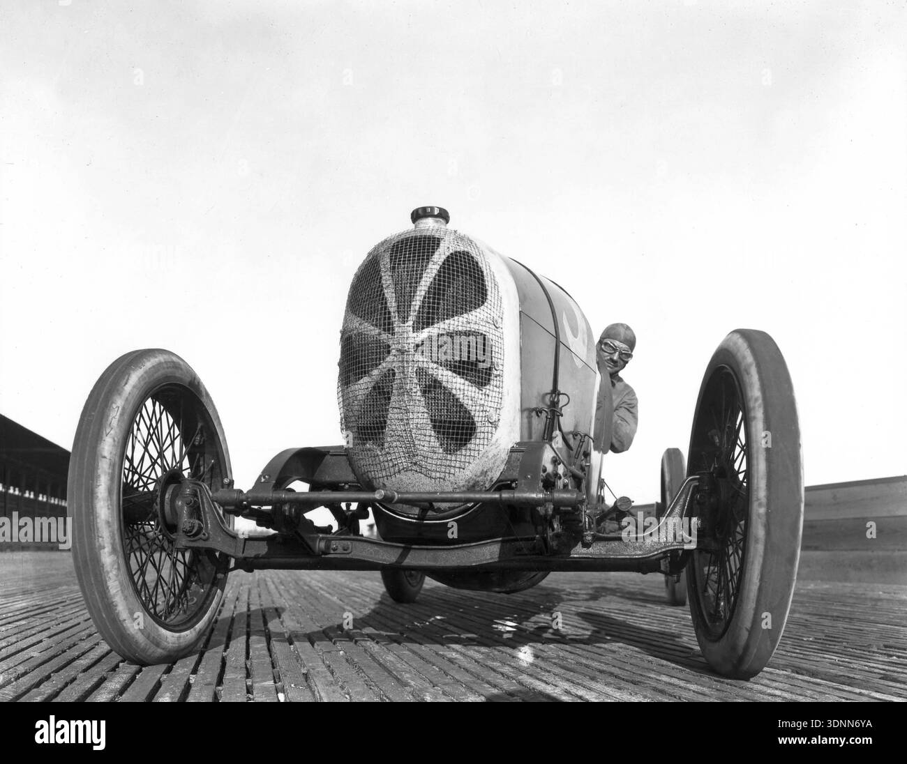 Roscoe Sarles blickt in diesem dramatischen Schwarzweißfoto aus dem Jahr 1920 mit einer Brille hinter das Gitterwerk seines Monroe-Rennwagens. Sarles nahm an der Tacoma Classic auf dem Tacoma Speedway teil, einer hölzernen Brettbahn. Stockfoto