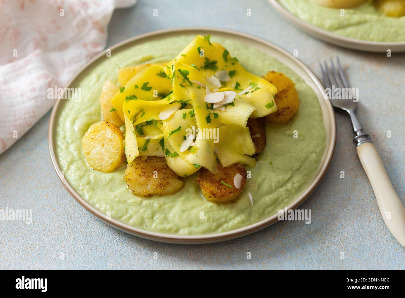 Gebackene Kartoffeln werden mit fermentierten Zucchini belegt und zusammen mit einer grünen Erbsensauce mit Brokkoli serviert. Diese Mahlzeit wird für ein gesundes Frühstück zubereitet Stockfoto