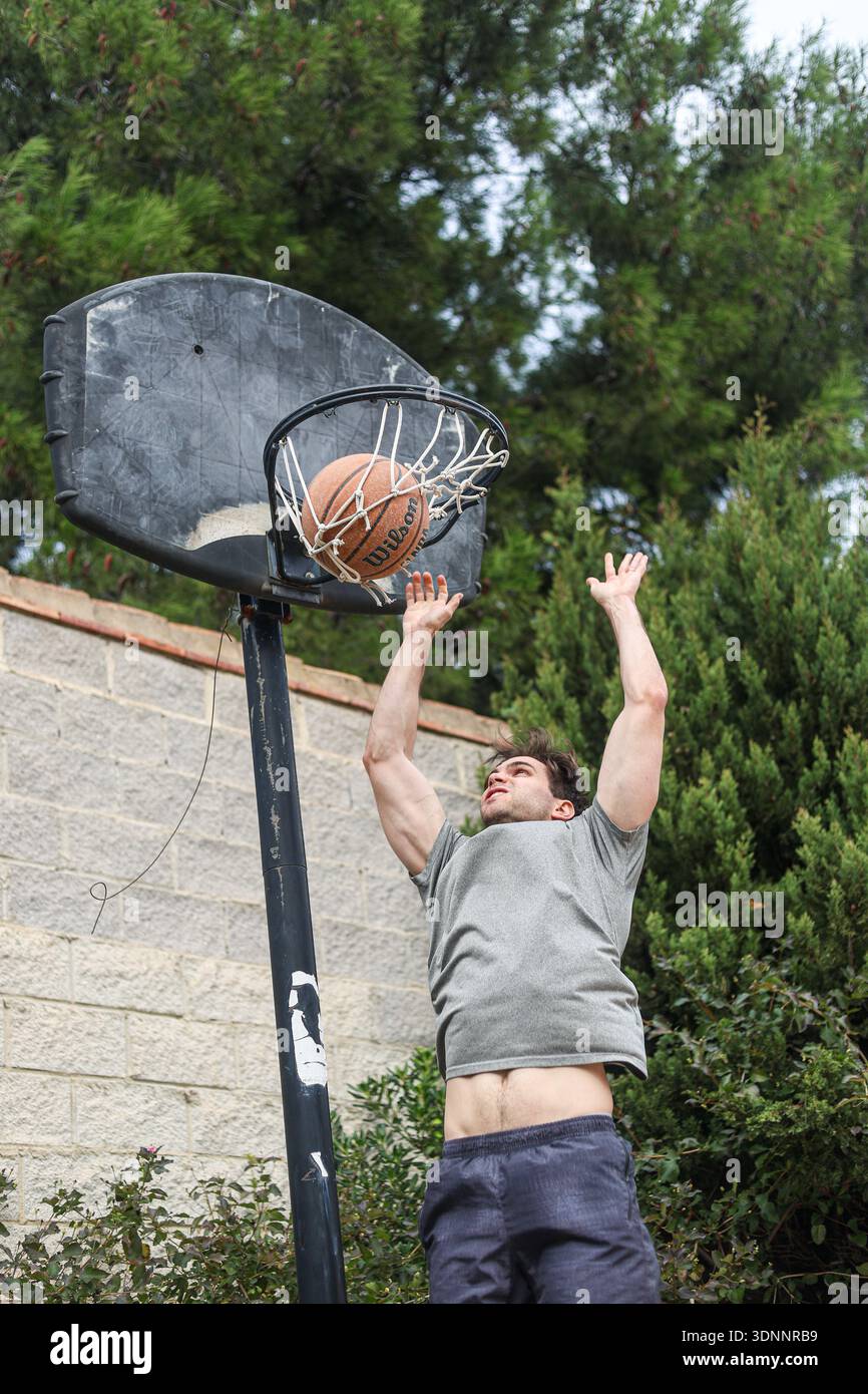 Junger Mann, der Basketball auf dem Outdoor Court spielt Stockfoto