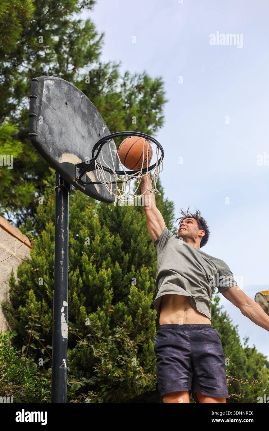 Junger Mann, der Basketball auf dem Outdoor Court spielt Stockfoto