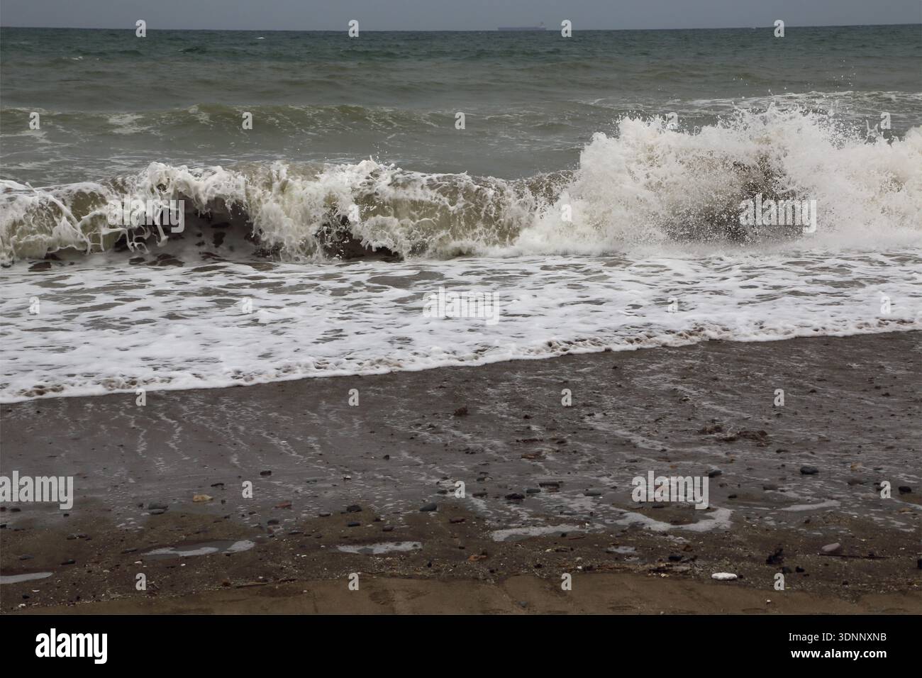 Raue Meereswellen stürzen zusammen, wenn die Flut am Chedi Beach Oman hereinkommt Stockfoto