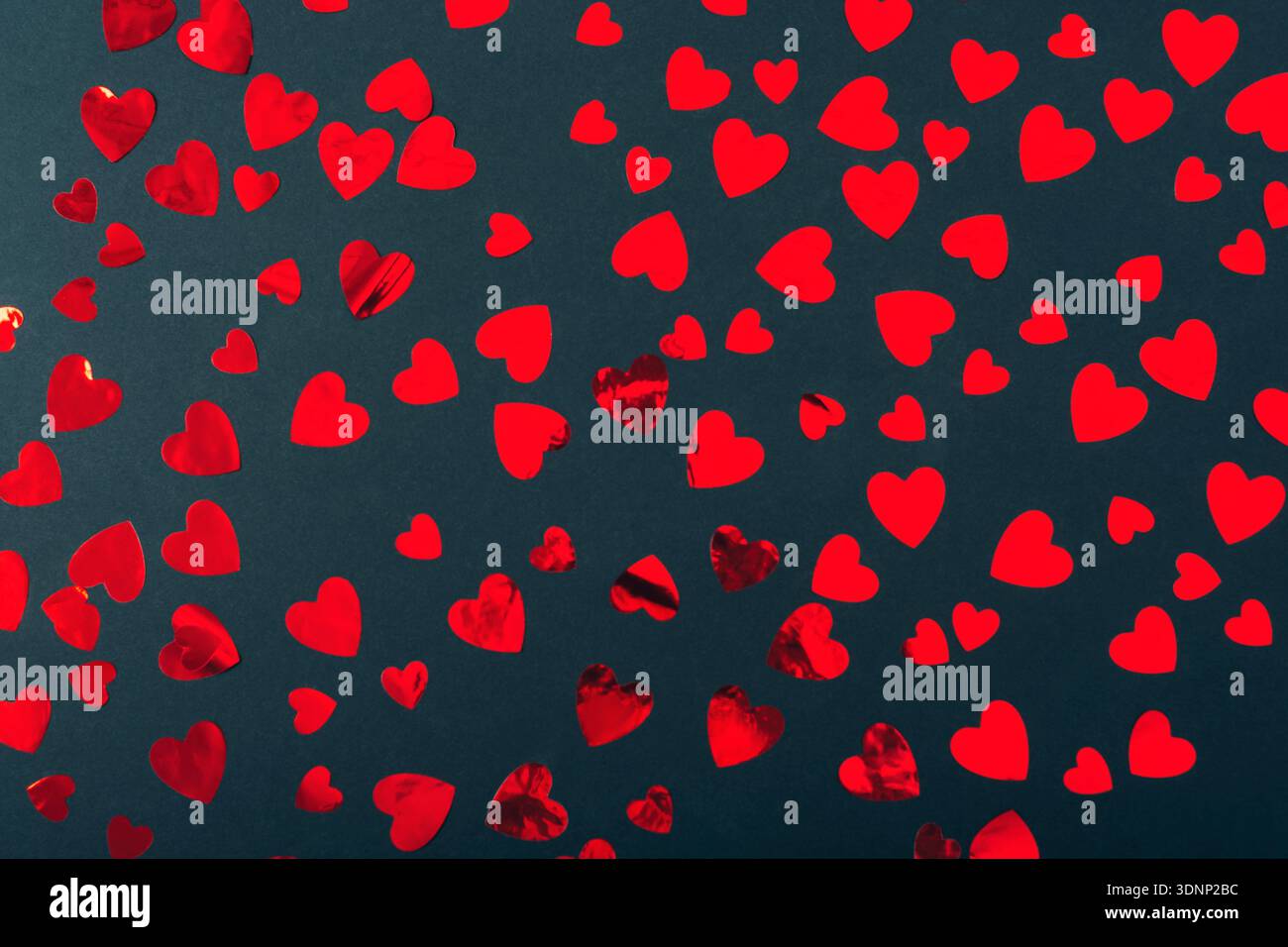Rote Papierherzen auf schwarzem Hintergrund verstreut. Valentinstag-Konzept. Draufsicht, flach. Stockfoto