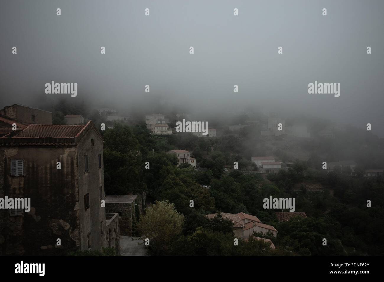 Nebliges Dorf Speloncato auf Korsika, Steinhäuser und Terrakottadächer, die durch niedrigen Bergnebel entstehen. Stockfoto