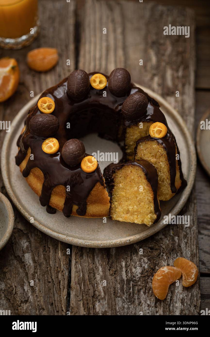 Bundt-Kuchen mit Zitrusfrüchten, Schokoladenglasur und Schokoladeneiern Stockfoto
