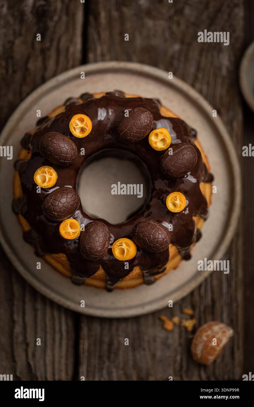 Bundt-Kuchen mit Zitrusfrüchten, Schokoladenglasur und Schokoladeneiern Stockfoto