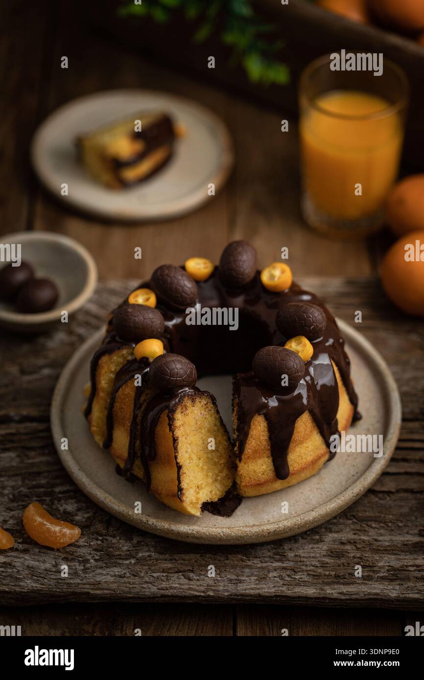 Bundt-Kuchen mit Zitrusfrüchten, Schokoladenglasur und Schokoladeneiern Stockfoto