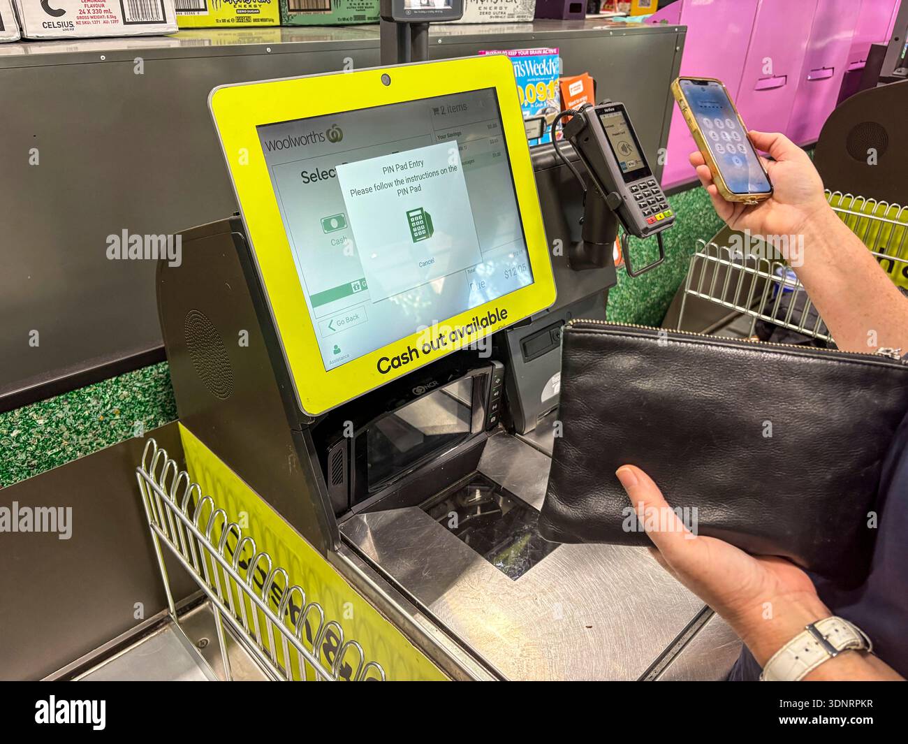 Supermarkt Selbstkontrolle Terrminal, Woolworths Supermarkt in Sydney Australien, Frau, die ihr iphone benutzt, um Lebensmittel anzuzapfen und zu bezahlen, Modell veröffentlicht - Smartphone-aufgenommenes Stockfoto