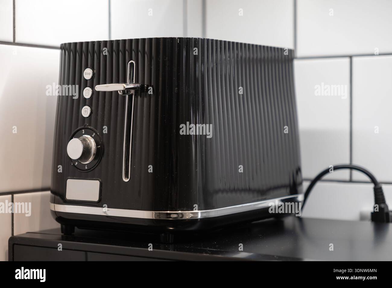 Nahaufnahme eines stilvollen schwarzen gerippten Toasters auf einer Küchenarbeitsplatte mit modernem Design für die bequeme tägliche Frühstückszubereitung und Stockfoto