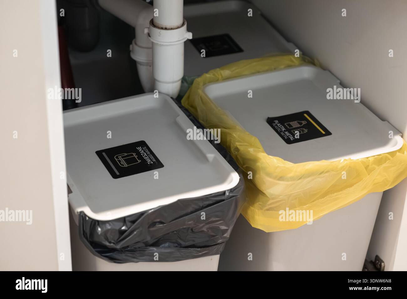 Nahaufnahme der Sortierbehälter für Haushaltsabfälle unter einer Küchentheke mit eindeutigen Etiketten für eine ordnungsgemäße Abfallentsorgung und ein nachhaltiges Wohnen Stockfoto