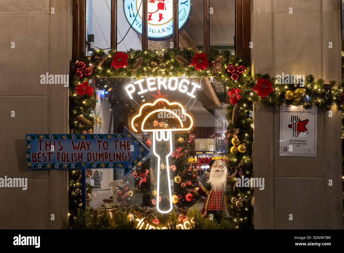 Krakau, Polen - 30. November 2025: Eingang des Restaurants mit festlicher Weihnachtsdekoration und einem einladenden Neon-Pierogi-Schild, das Tradition anbietet Stockfoto
