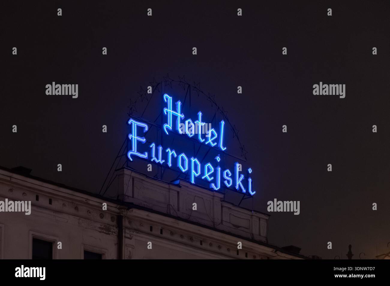 Krakau, Polen - 30. November 2025: Das leuchtend blaue Neonschild des Hotels Europejski zeigt die historische Dachfassade bei Nacht und unterstreicht das einzigartige Europea Stockfoto