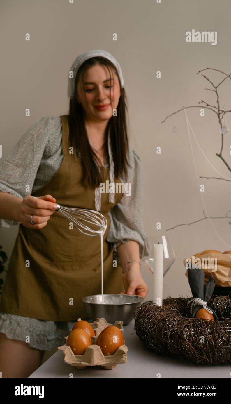 Familie Ostertraditionen, Frau, die Glasur für Osterkuchen in einer warmen und gemütlichen Wohnküche-Atmosphäre vorbereitet. Stockfoto