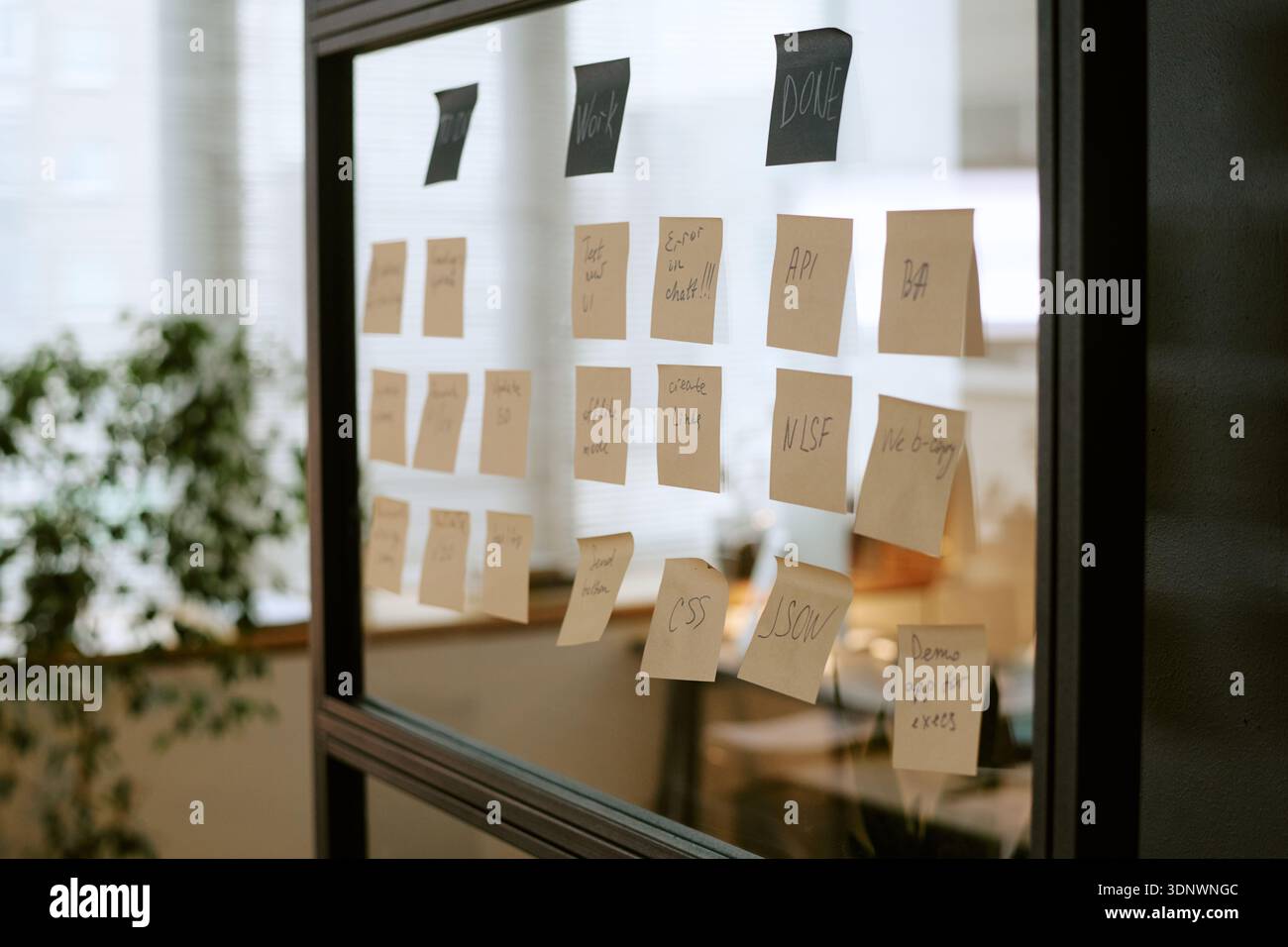 Organisation von Geschäftsabläufen mithilfe von Haftnotizen auf Glaswand im Büro Stockfoto