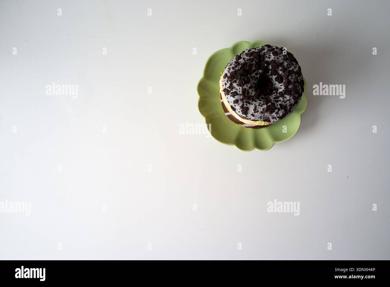 Gestapelte Donuts auf Platte asymmetrische Donutflachlage auf grüner Platte, exzentrische Zusammensetzung mit großzügigen Stockfoto