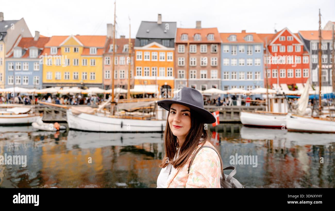 Ein Besucher genießt die lebhafte Atmosphäre von Nyhavn in Kopenhagen, Dänemark, mit farbenfrohen historischen Gebäuden und traditionellen Booten entlang der malerischen Landschaft Stockfoto