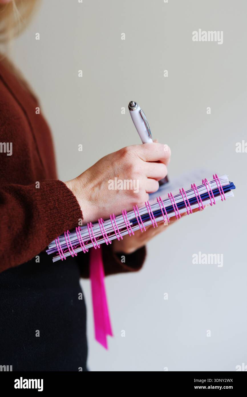 Weibliche Hände halten Notizbuch und schreiben mit Stift. Bildungswesen, Journalwesen und Arbeitsorganisationskonzept mit Kopierraum. Stockfoto