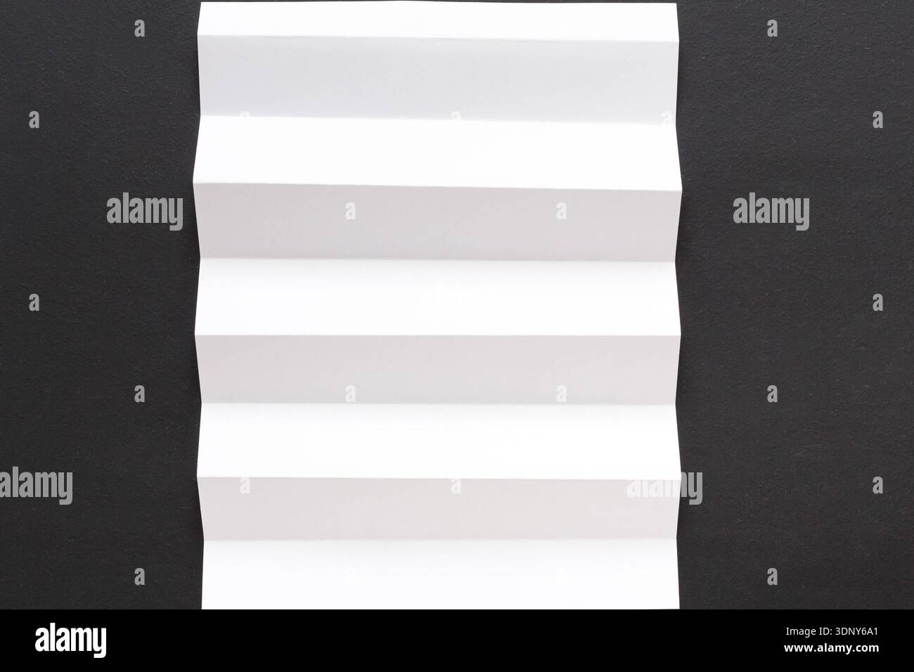 Weißes gefaltetes Blatt Papier auf schwarzem Hintergrund Stockfoto