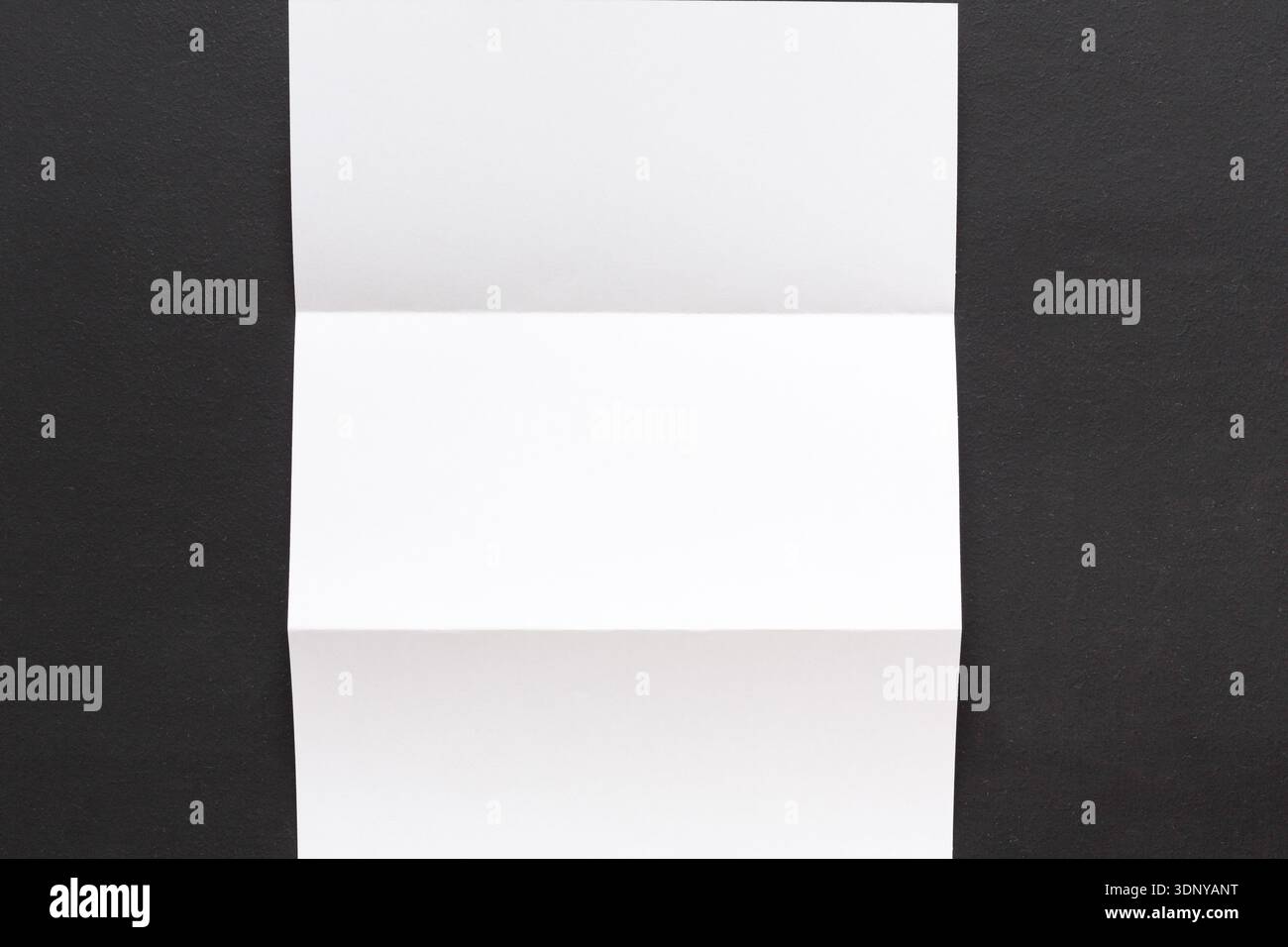 Weißes gefaltetes Blatt Papier auf schwarzem Hintergrund Stockfoto
