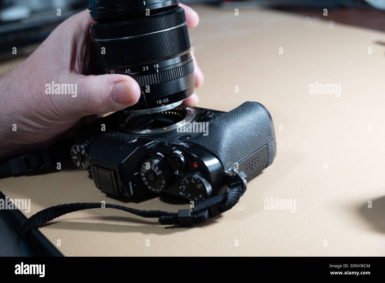 Mit der Hand wird ein Objektiv an einer Digitalkamera befestigt, um die Aufnahme von Bildern vorzubereiten. Stockfoto