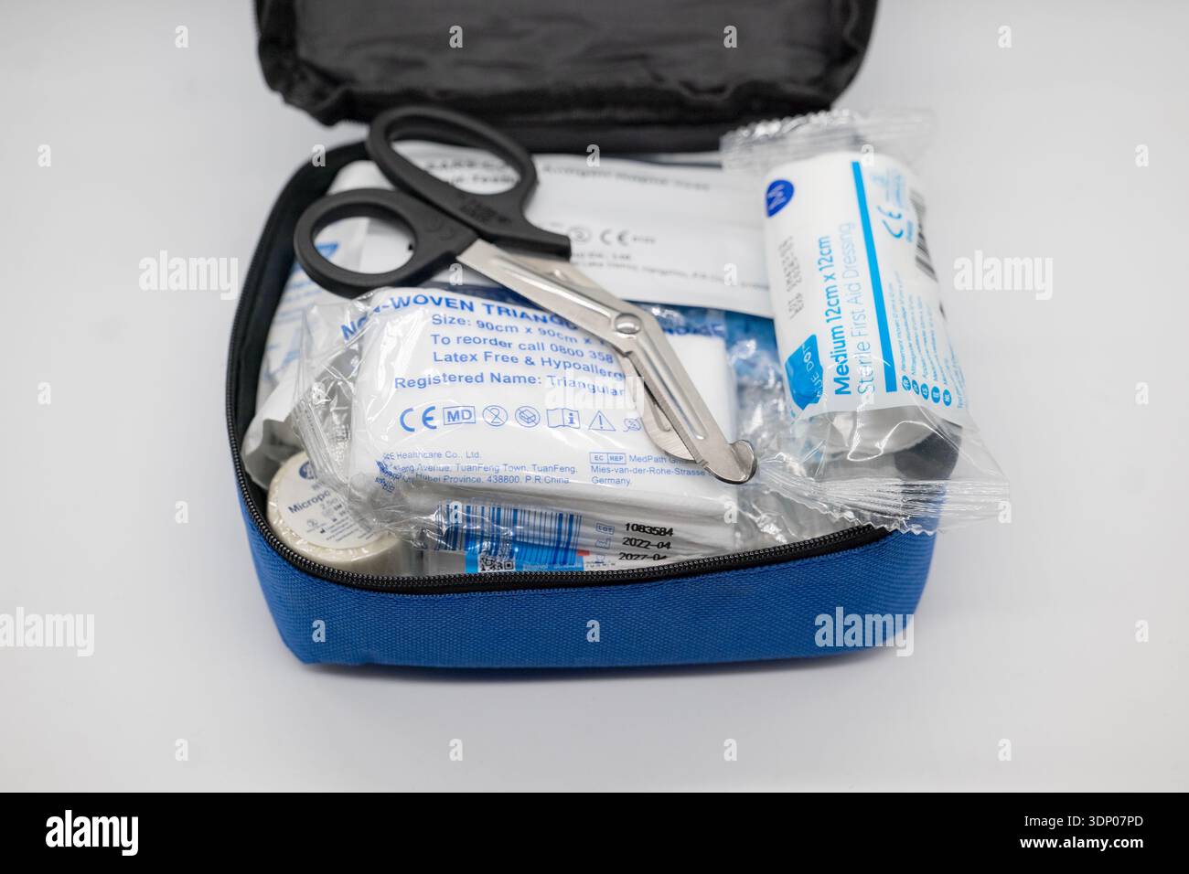 Modernes erste-Hilfe-Set mit Verbänden und Schere vor weißem Hintergrund, medizinische Notversorgung Stockfoto