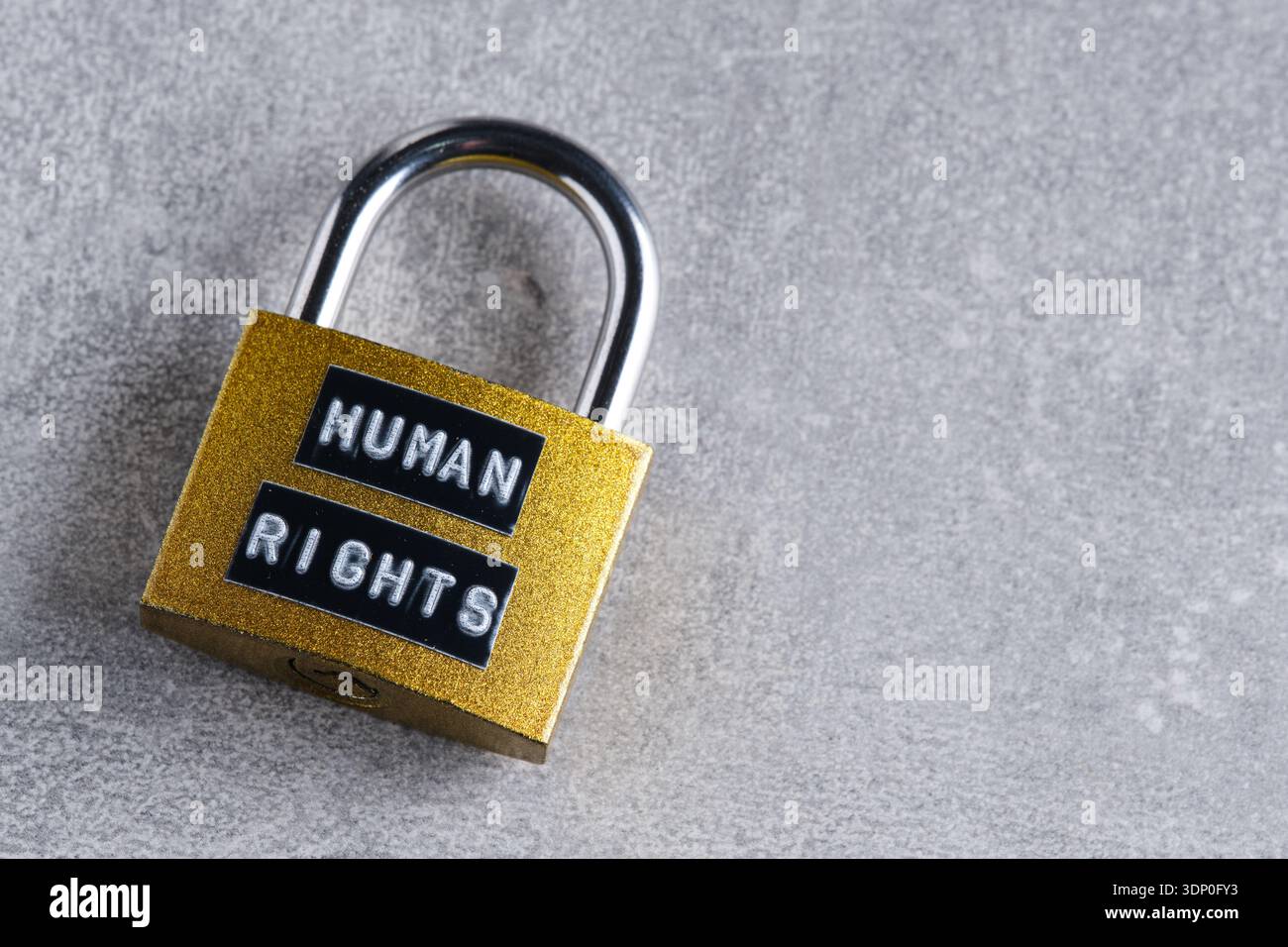 Geschlossenes "MENSCHENRECHTS"-Schloss auf neutralem grauen Hintergrund, aus einem Winkel geschossen. Minimalistische Zusammensetzung, geeignet für legales Design und Artikel Stockfoto